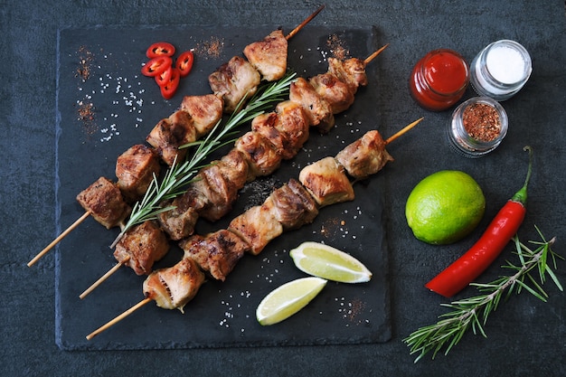 Kebab apetitoso com especiarias, pimenta e limão. Espetos de carne de porco perfumada em uma placa de pedra.