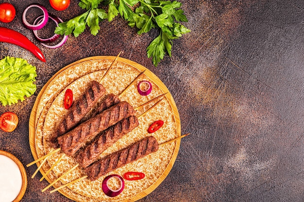 Kebab de carne tradicional del Medio Oriente, árabe o mediterráneo con verduras y pan lavash. Vista superior.