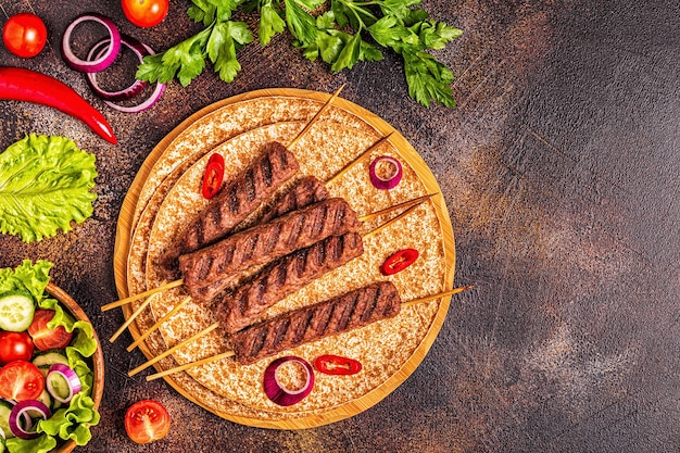 Kebab de carne tradicional del Medio Oriente, árabe o mediterráneo con verduras y pan lavash. Vista superior.