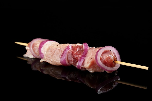 Kebab de cerdo crudo sobre fondo negro