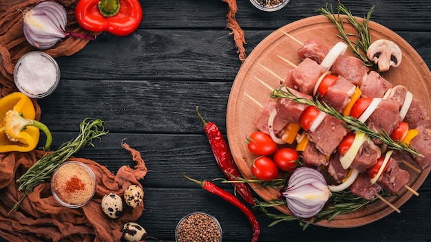 Kebab cru de carne em um fundo de madeira com legumes Vista superior Espaço livre para texto