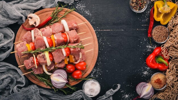 Kebab cru de carne em um fundo de madeira com legumes Vista superior Espaço livre para texto