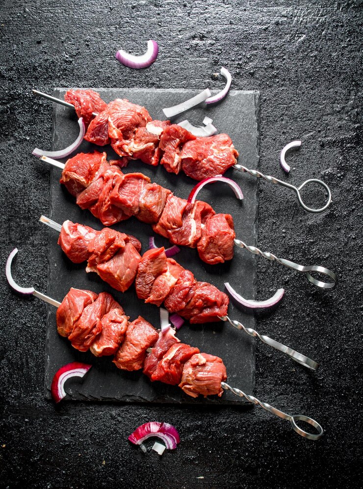 Kebab de carne crua em uma placa de pedra com pedaços de cebola