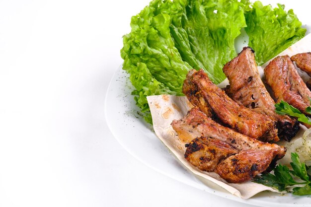 Kebab de carne nas costelas em lavash com cebola e repolho em um prato branco, em um fundo branco isolado