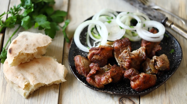 Kebab frito com cebola crua em um prato.