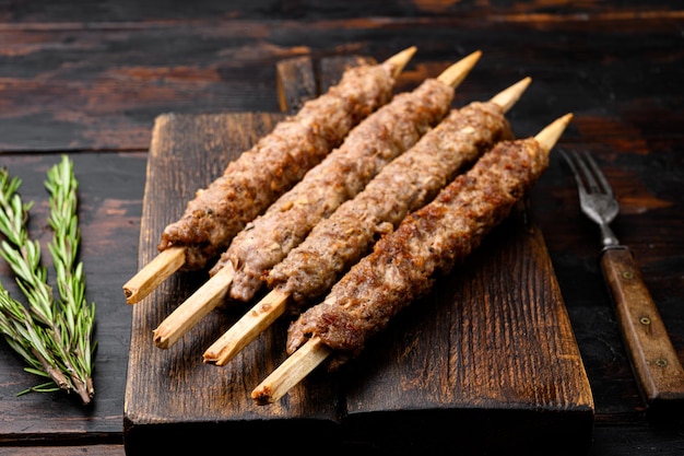 Kebab de Lula a la parrilla en brochetas con especias, en una tabla de servir, en un viejo fondo de mesa de madera oscura