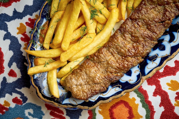 Kebab de lula turco tradicional hecho de carne picada servido en un plato con papas fritas