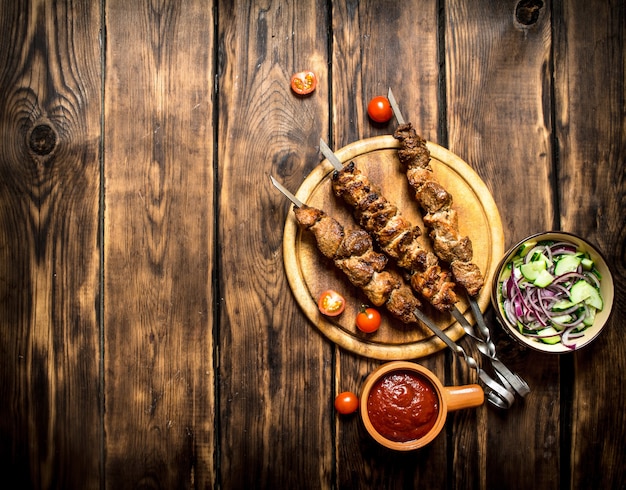 Kebab mit frischem Salat aus Gurken und Zwiebeln. Auf hölzernem Hintergrund.