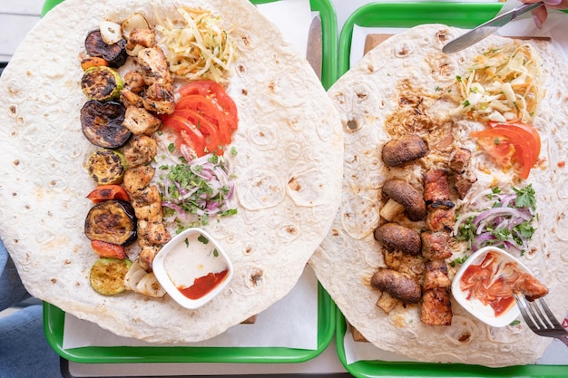 Kebab a la parrilla con pan de pita y verduras en la bandeja en la vista superior del café de la calle de comida rápida de verano