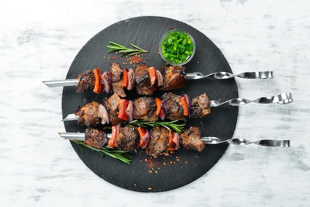 Kebab tradicional Brochetas de cerdo jugosas con verduras en un plato de piedra negra Barbacoa Vista superior Espacio libre para texto