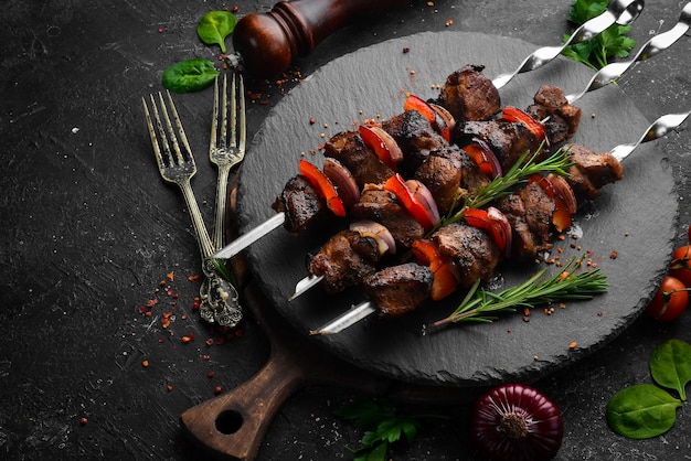 Kebab tradicional Brochetas de cerdo jugosas con verduras en un plato de piedra negra Barbacoa Vista superior Espacio libre para texto