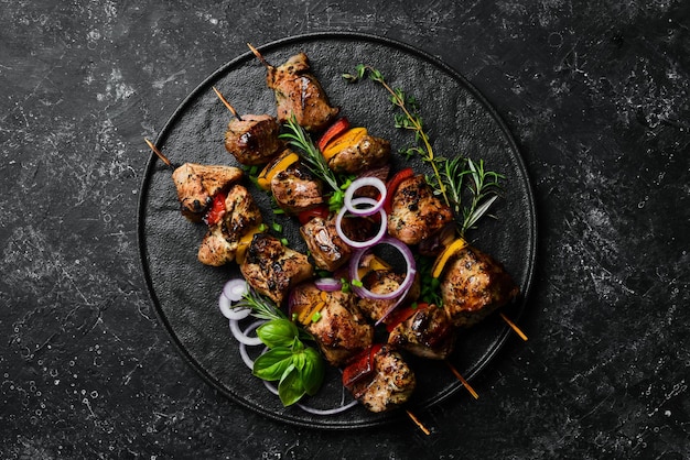 Kebab tradicional Brochetas de cerdo jugosas con verduras en un plato de piedra negra Barbacoa Vista superior Espacio libre para texto