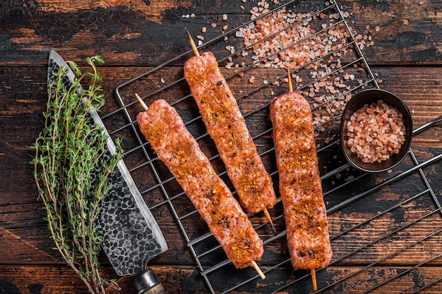 Kebab de Urfa cruda sin cocer en una parrilla con sal rosa Vista superior de fondo de madera