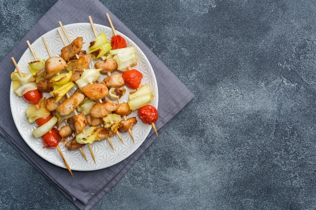 Kebabhuhn, -Zucchini und -tomaten auf Aufsteckspindeln in einer Platte.