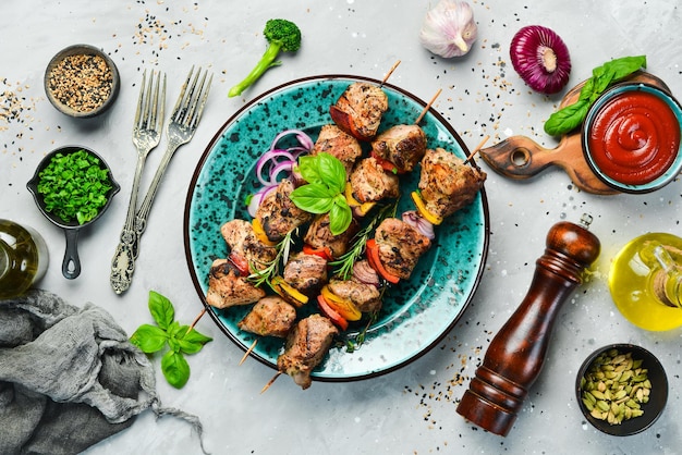 Kebabs brochetas de carne a la parrilla shish kebab con verduras en un plato En una mesa antigua de hormigón Vista superior