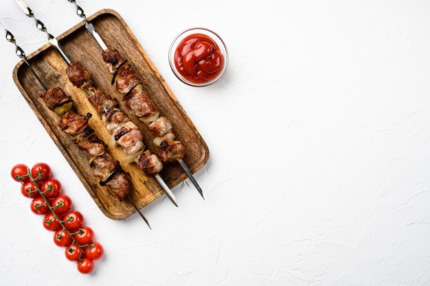 Kebabs gegrillte Fleischspieße, Schaschlik-Set, auf weißem Steintischhintergrund, Draufsicht flach, mit Kopienraum für Text