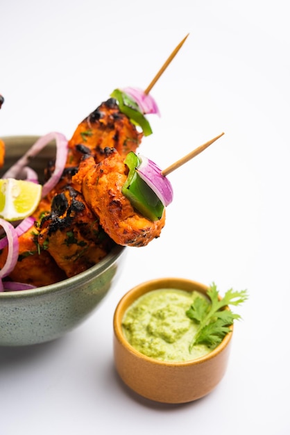 Kebabs tikka de frango indiano, marinado em especiarias e iogurte e assado em tandoor. servido com chutney verde e cebola. foco seletivo