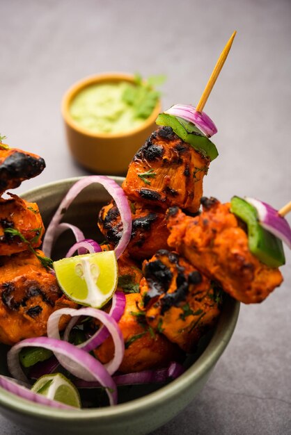 Kebabs tikka de frango indiano, marinado em especiarias e iogurte e assado em tandoor. servido com chutney verde e cebola. foco seletivo