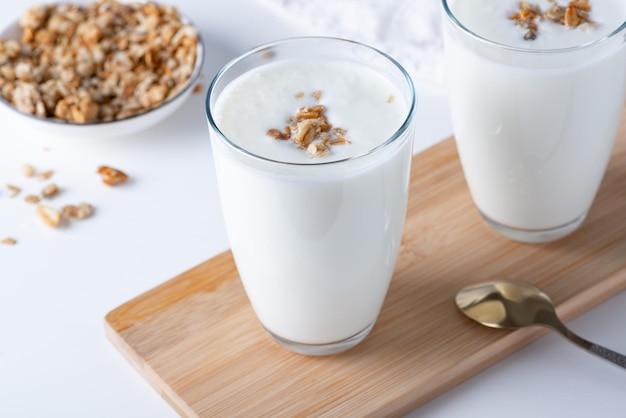 Kefir-Buttermilch oder Joghurt mit Müsli Joghurt im Glas auf weißem Holzhintergrund