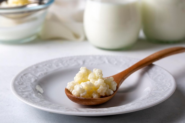 Kefir fermentiertes Milchgetränk mit Kefirkörnern. Selbstgemachter Kefir steht in einem Glas neben Kefirknollen und Milch