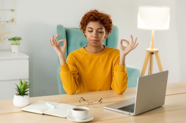 Kein Stress, Ruhe bewahren. Achtsame afrikanische Geschäftsfrau praktiziert Atemübungen im Home Office