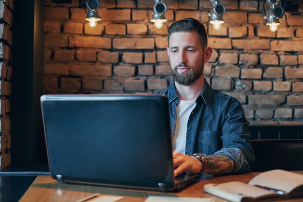 Keine Minute ohne meinen Laptop. Schöner junger Mann arbeitet an seinem Laptop, während er Kaffee im Café genießt.