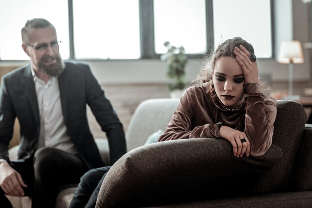 Keine Wünsche haben. Lockige Tochter mit dunklem Make-up, die nicht mit ihrem fürsorglichen, besorgten Vater sprechen möchte