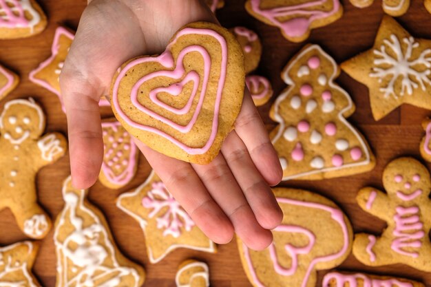 Kekse für Valentinstag in Frauenhänden im Hintergrund des Lebkuchens.