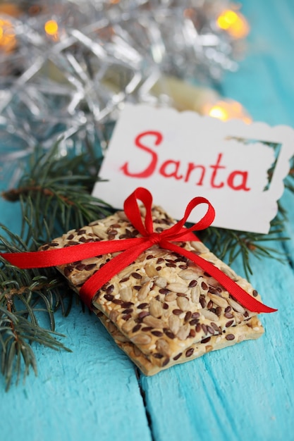 Kekse mit Leinsamen und Sonnenblume mit einer Karte, die Santa sagt. Geschenk auf blauem Holztisch