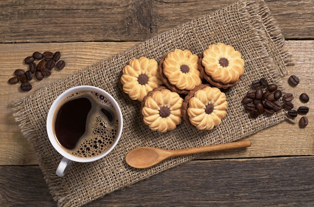 Kekse mit Schokolade und heißem Kaffee auf altem Holztisch, Ansicht von oben