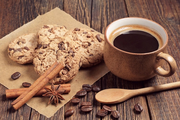 Kekse mit Schokolade und Tasse Kaffee auf dunklem Holztisch