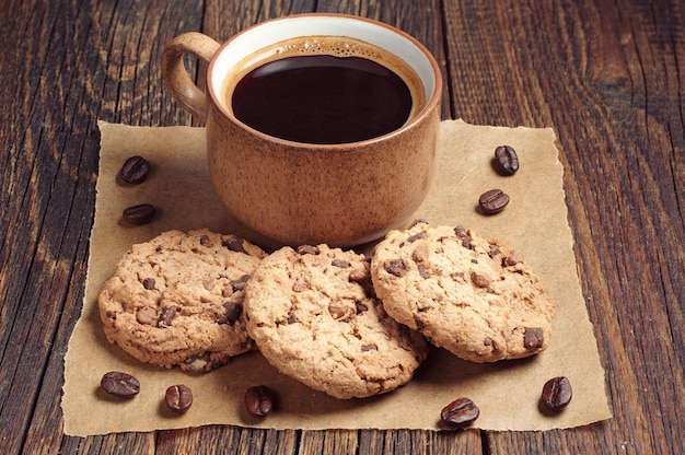 Foto kekse mit schokolade und tasse schwarzem kaffee auf altem holztisch