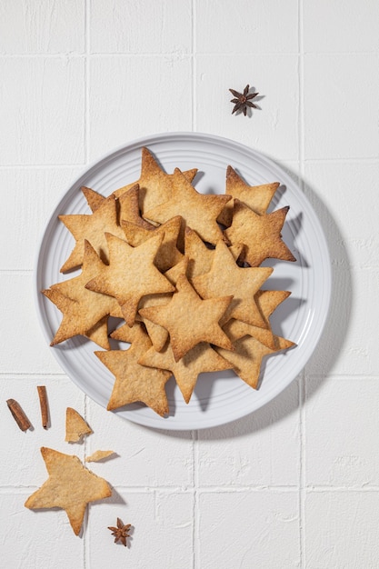 Kekse mit Zimt in Form von Sternen auf einem Teller auf weißem Hintergrund für das neue Jahr