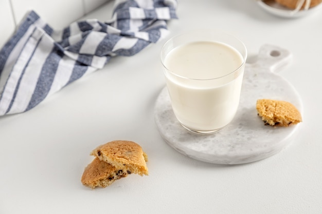 Kekse und Milch in einem Glas auf einem weißen Tisch mit einer Serviette