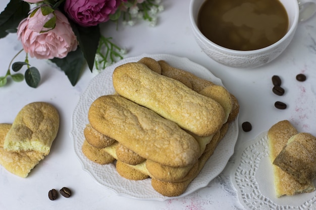 Kekskekse Savoyardi, Kaffee und Blumen auf einer weißen Marmoroberfläche