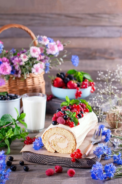 Keksrolle mit Mascarponecreme und Beeren, Minzblätter auf hölzernem Hintergrund. Sommer Food Konzept