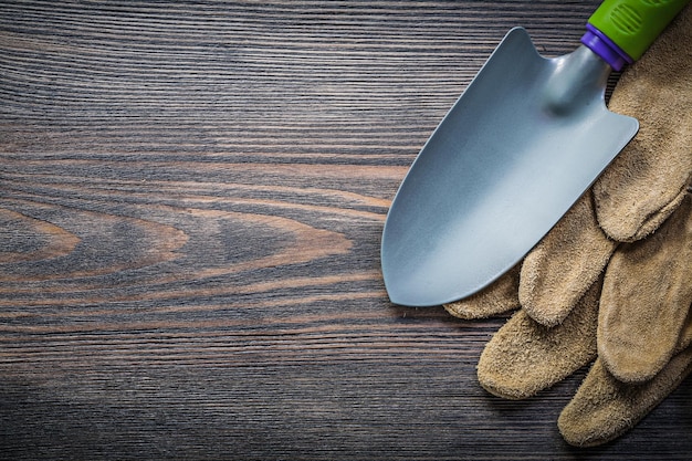 Kellenpaar Lederschutzhandschuhe auf Holzbrett direkt über dem Gartenkonzept