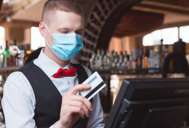 Kellner arbeitet in einem Restaurant in einer medizinischen Maske.