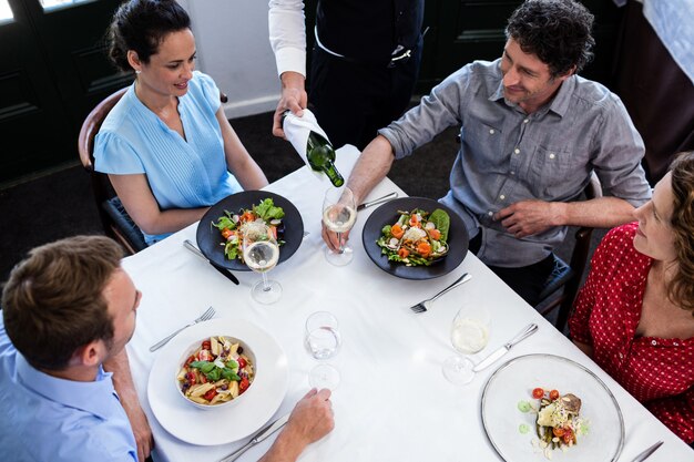 Kellner, der der Gruppe von Freunden Wein beim Mittagessen serviert