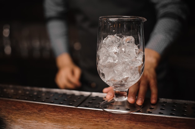 Kellner, der ein glas gefüllt mit eiswürfeln hält