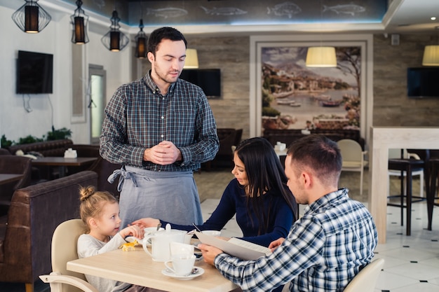 Kellner gibt Menü an glückliche Familie im Café