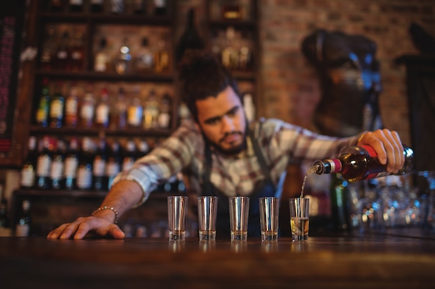 Foto kellner gießt tequila in schnapsgläser an der theke