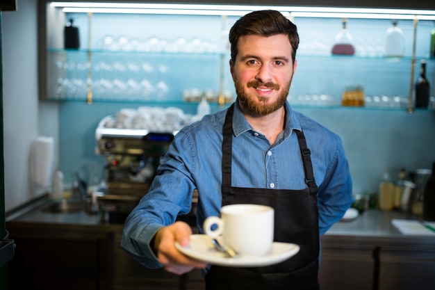 Kellner hält Tasse Kaffee