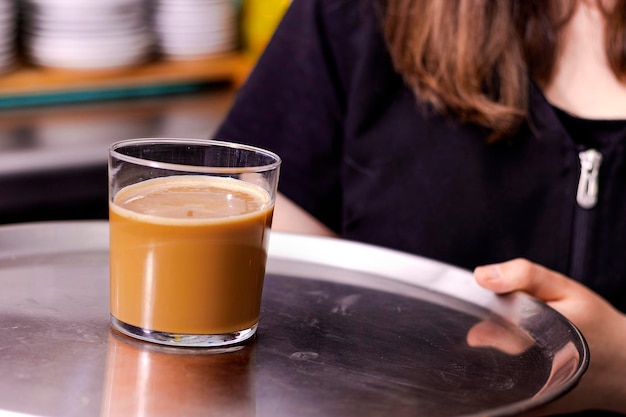 Kellner in schwarzer Schürze streckt eine Tasse Kaffee