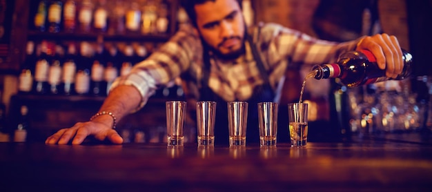 Kellner schenkt Tequila an der Theke in Schnapsgläser ein