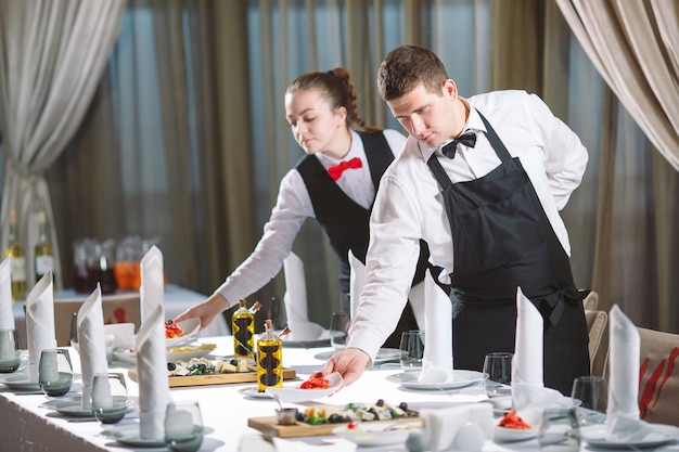 Kellner servieren Tisch im Restaurant und bereiten sich auf den Empfang der Gäste vor.