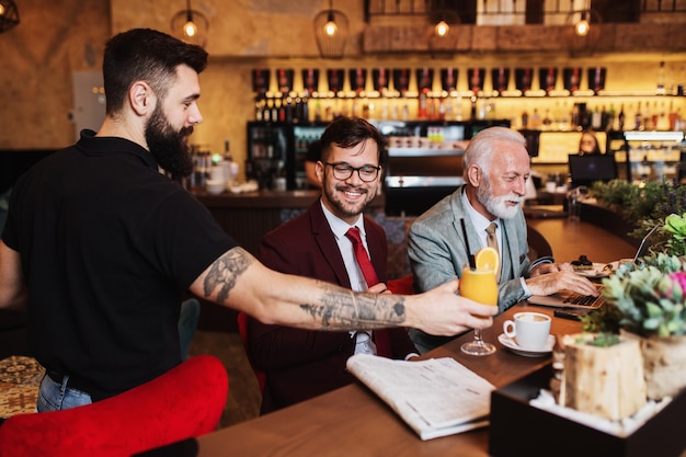 Kellner serviert den Geschäftsleuten im Restaurant ein Getränk?