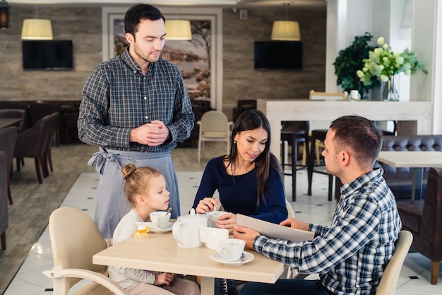 Foto kellner serviert eine familie in einem restaurant