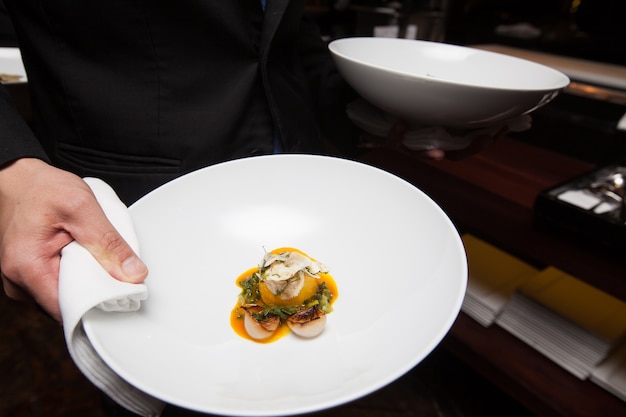 Kellnerin hält Tablett Lebensmittel zum Abendessen im Hotel Restaurant Küche