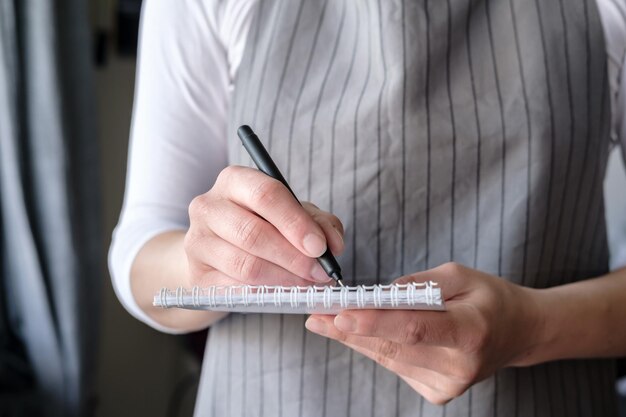 Kellnerin mit Notizbuch und Stift nimmt die Bestellung eines Kunden entgegen und schreibt sie in den Notizblock